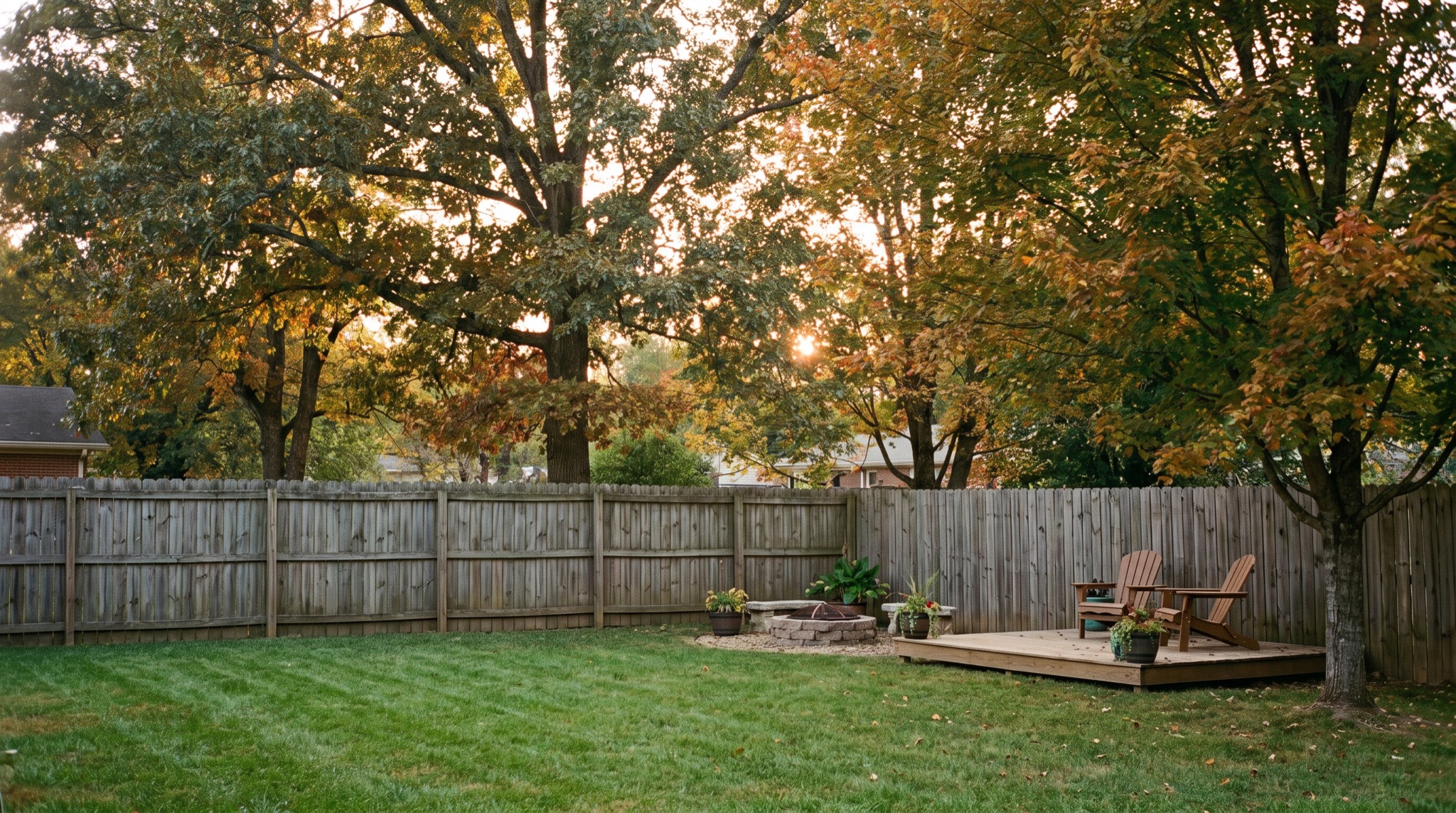 A tidy East Tennessee backyard with mature hardwoods and a timber fence at golden hour
